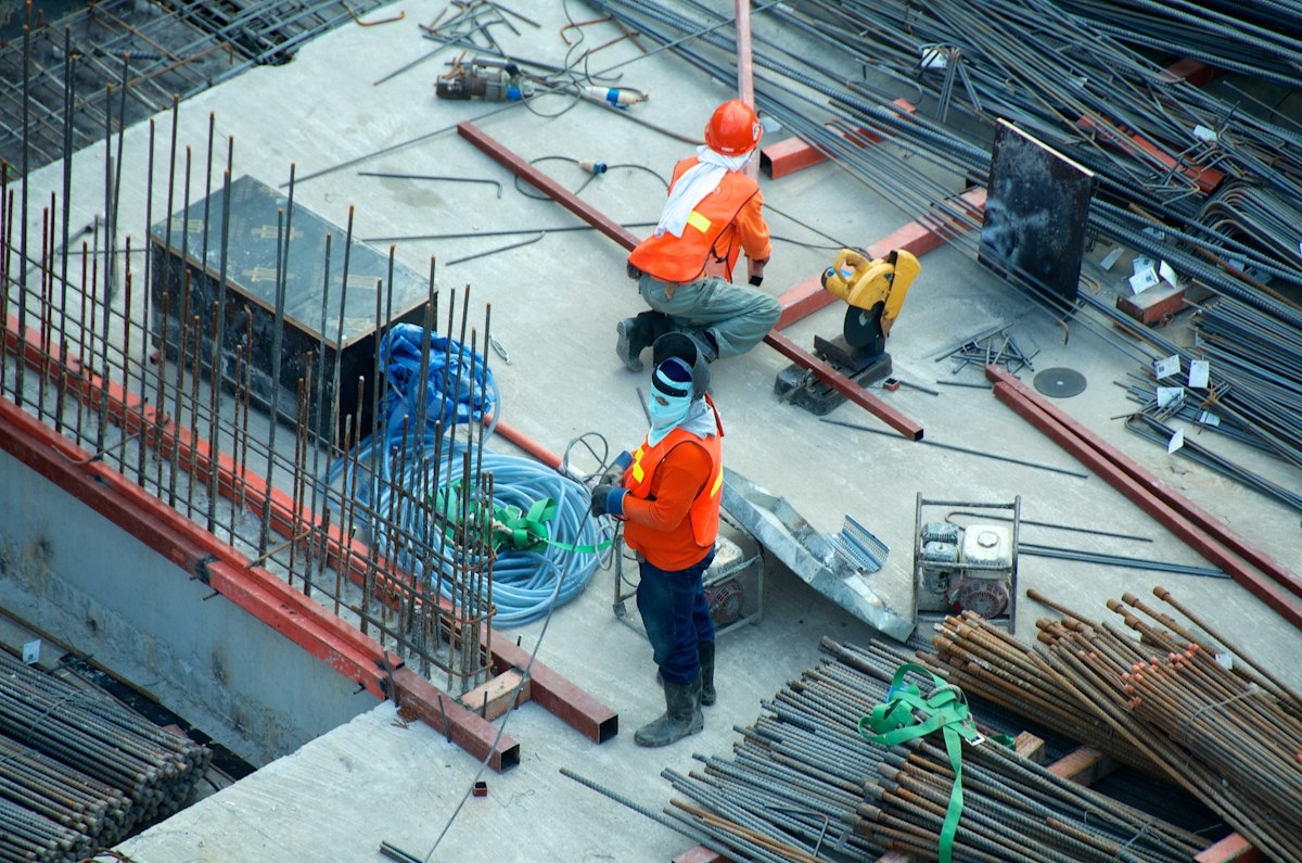 Trabajadores de construcción sobre andamios en una obra con equipo de seguridad